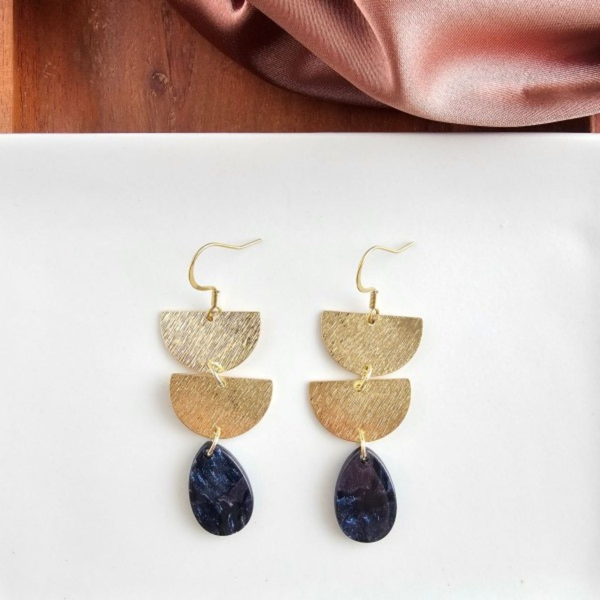 Gold earrings with purple teardrop stones on a white background