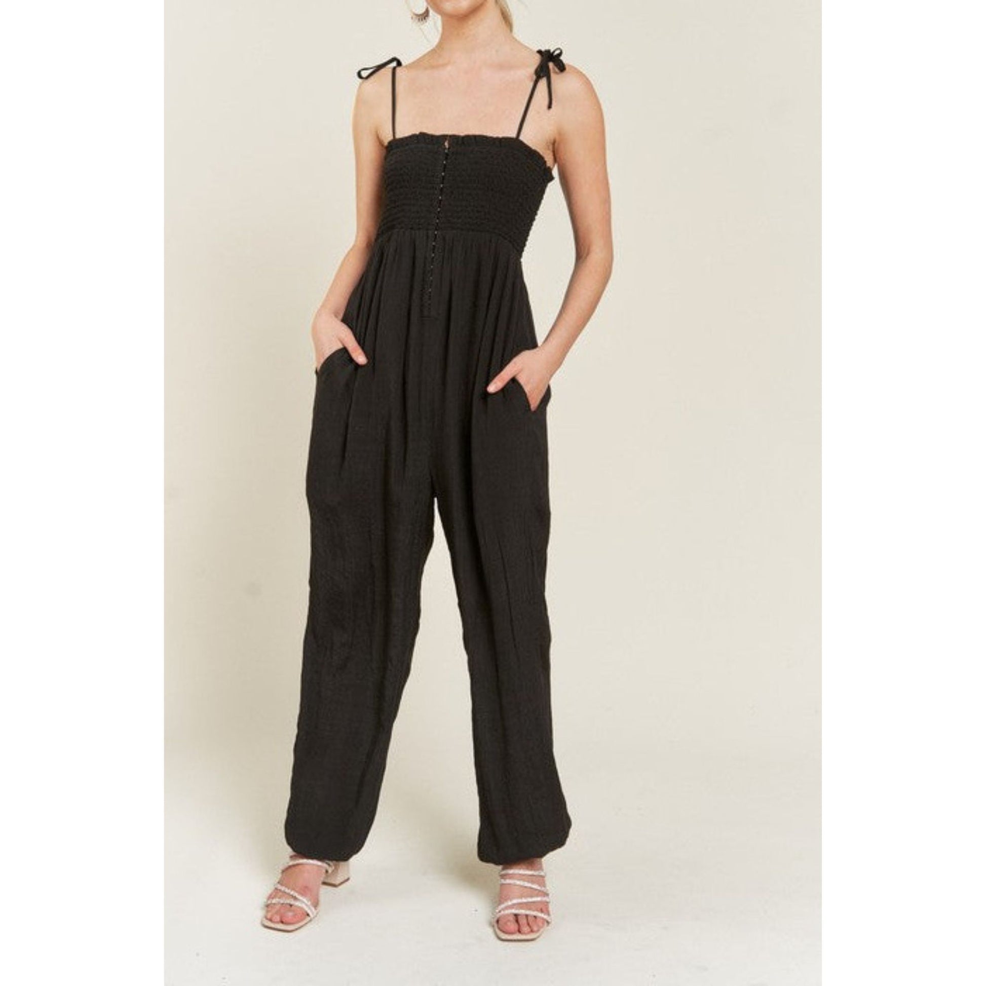 Black jumpsuit worn by a model on a beige background