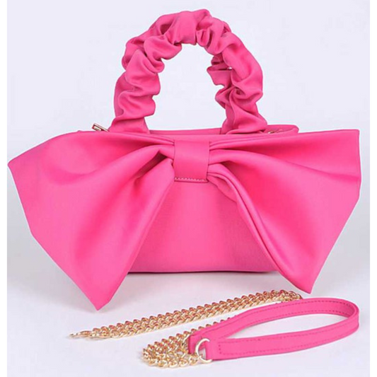 Pink handbag with a large bow and gold chain strap on a white background