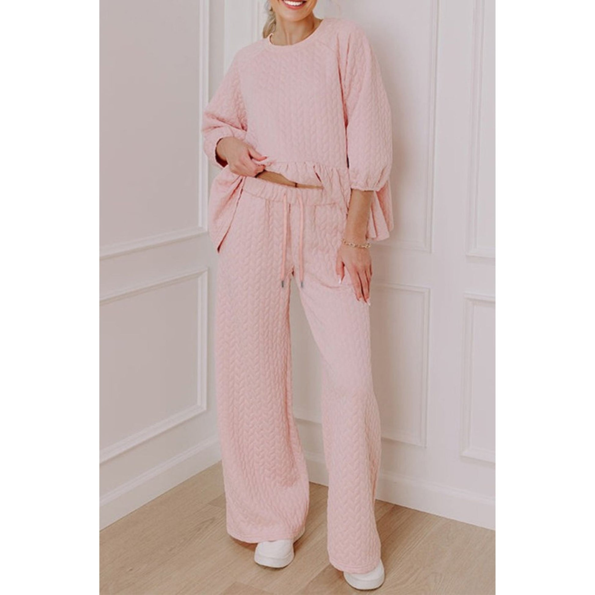 Person wearing a pink textured outfit in a minimalistic room.