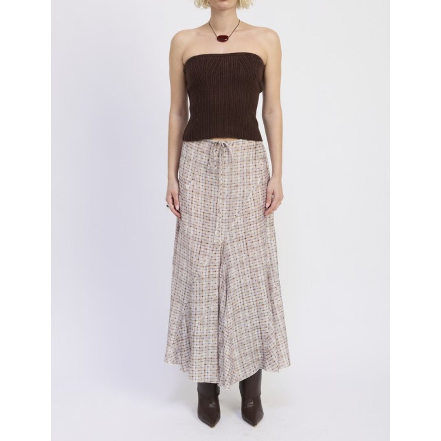 Person wearing a strapless brown top and plaid skirt on a white background