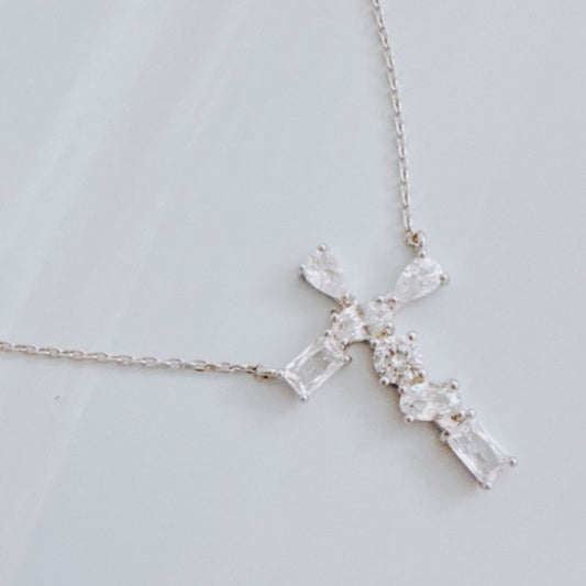 Crystal cross necklace on a light gray background