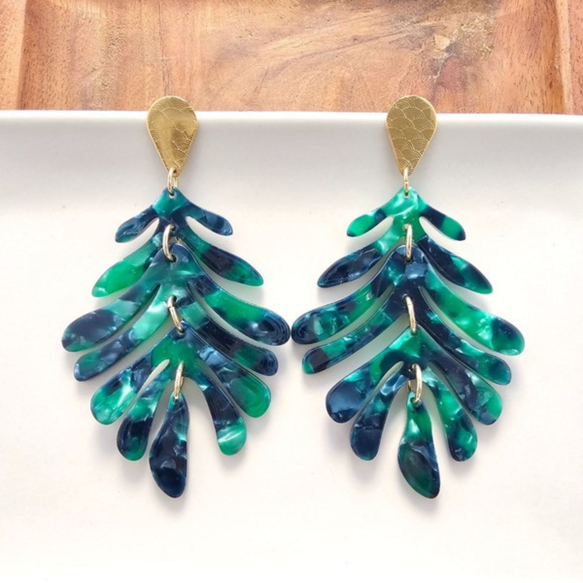 Pair of green and blue leaf-shaped earrings on a white background