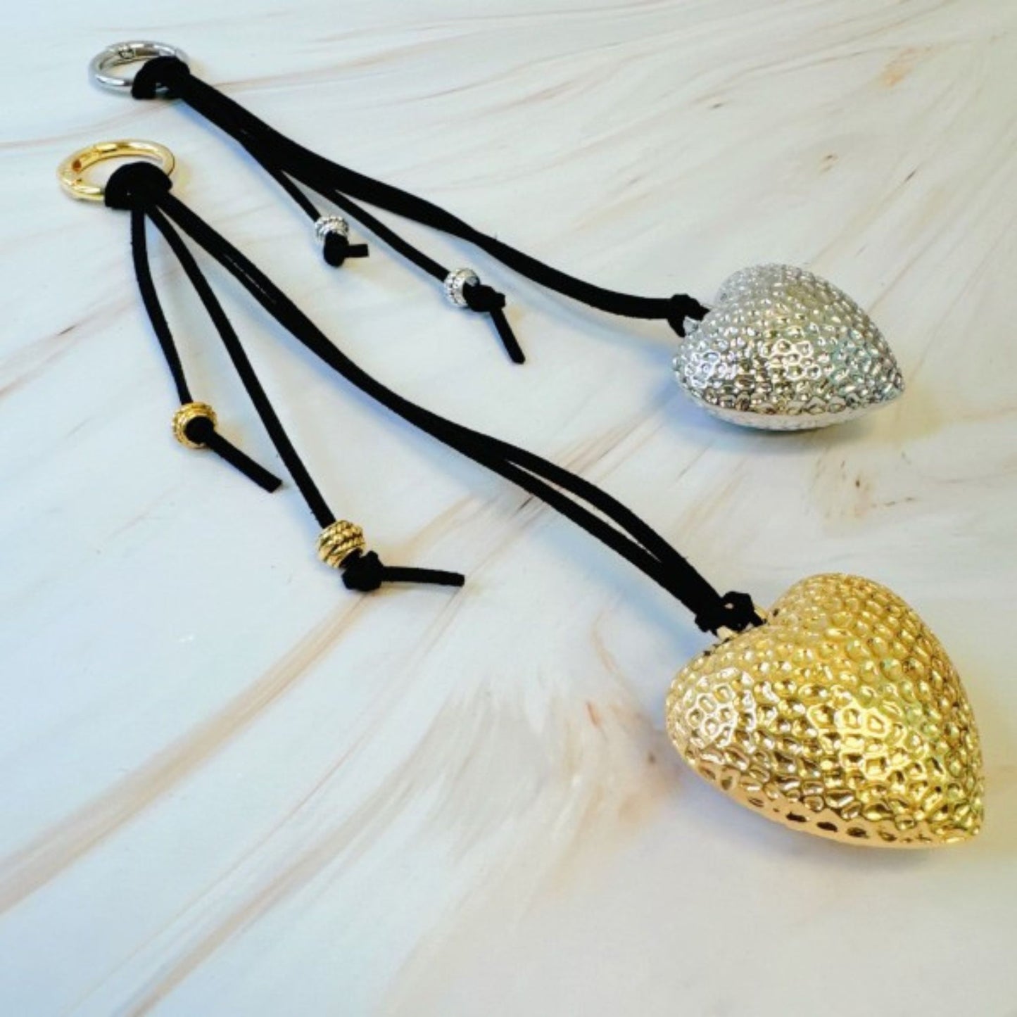 Heart-shaped keychains in gold and silver on a light wooden surface