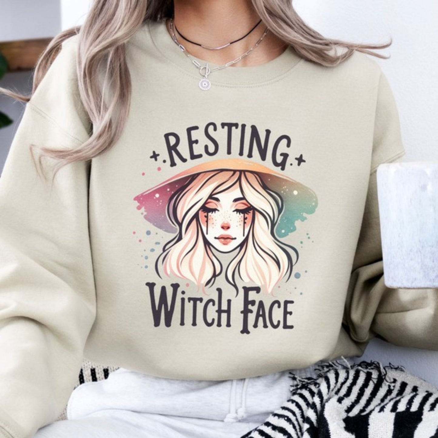 Sand sweatshirt with 'Resting Witch Face' design and a person wearing it.