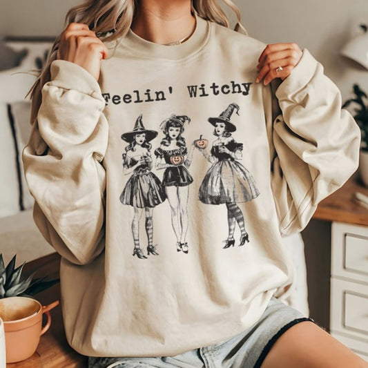 Person wearing a beige sweatshirt with Halloween-themed graphics and text.