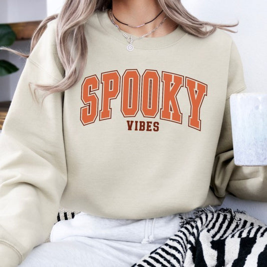 Beige sweatshirt with 'SPooky Vibes' text worn by a person.