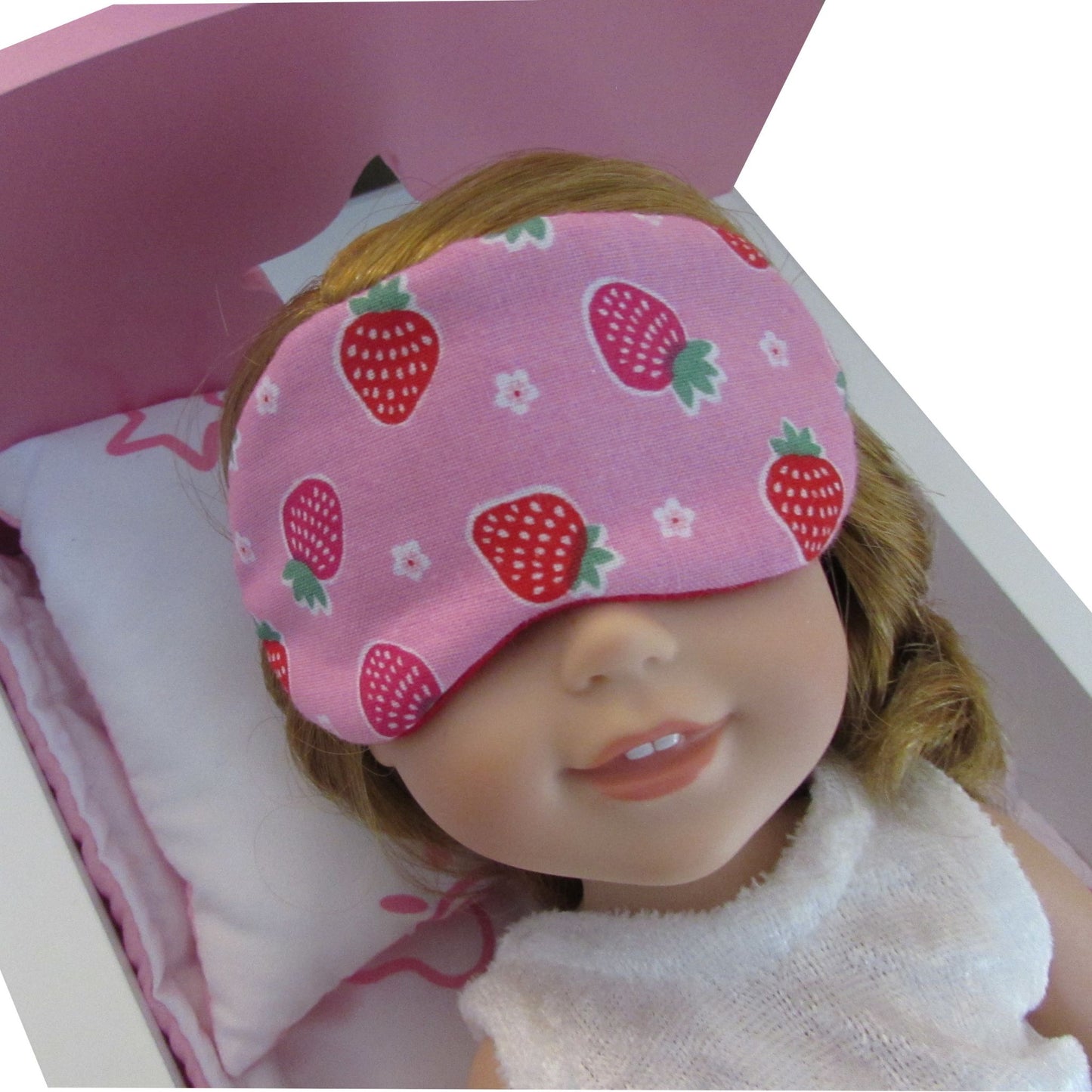 Doll wearing a pink sleep mask with strawberry pattern on a white background