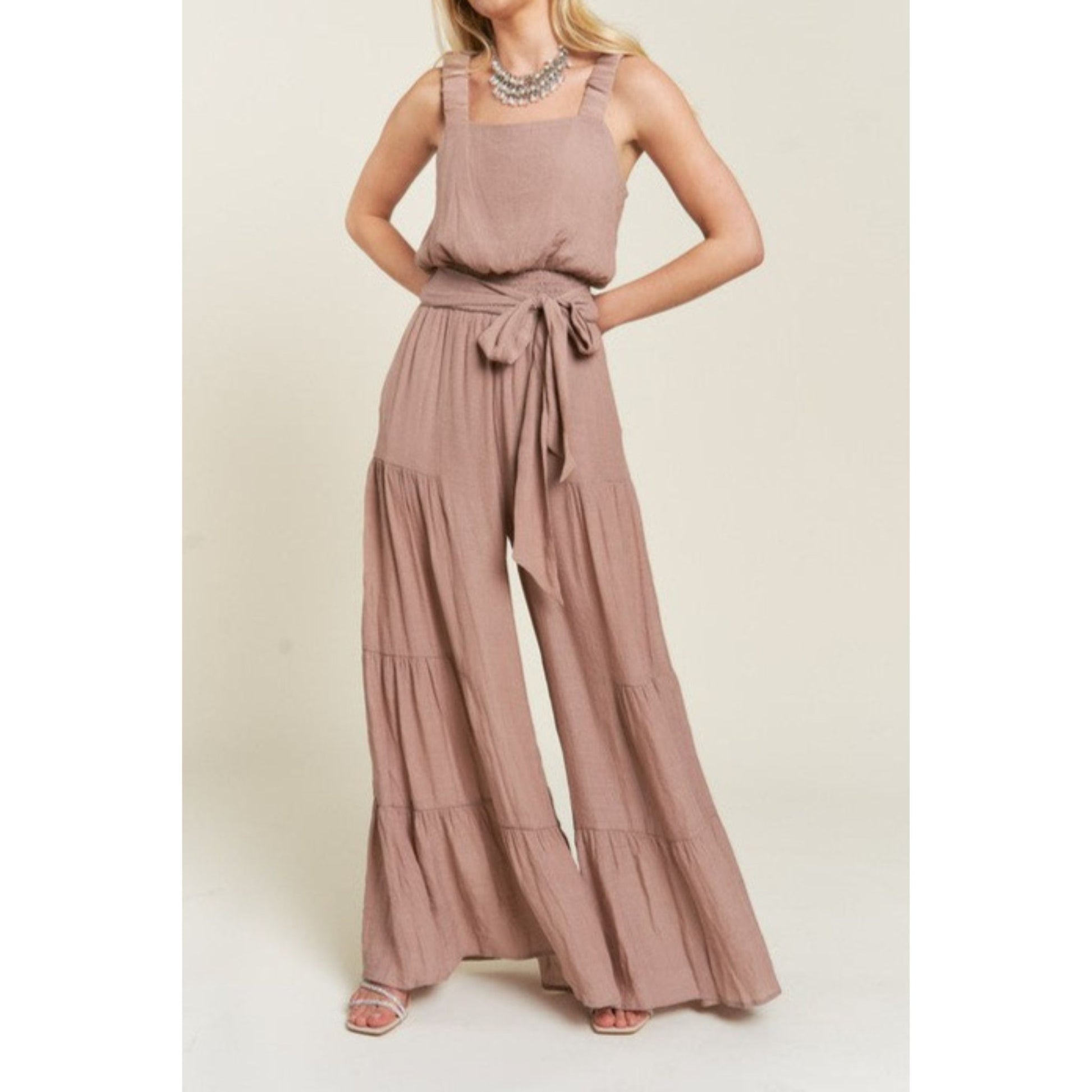 Woman wearing a taupe jumpsuit on a beige background