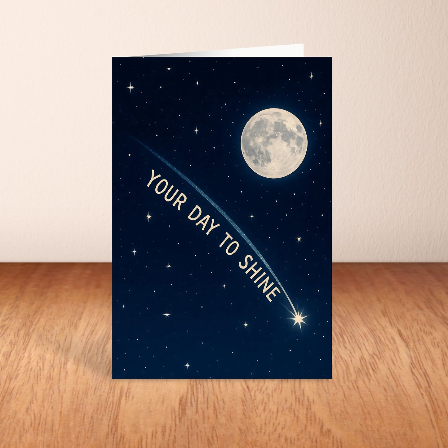 Greeting card with a night sky design, moon, and stars on a wooden surface.