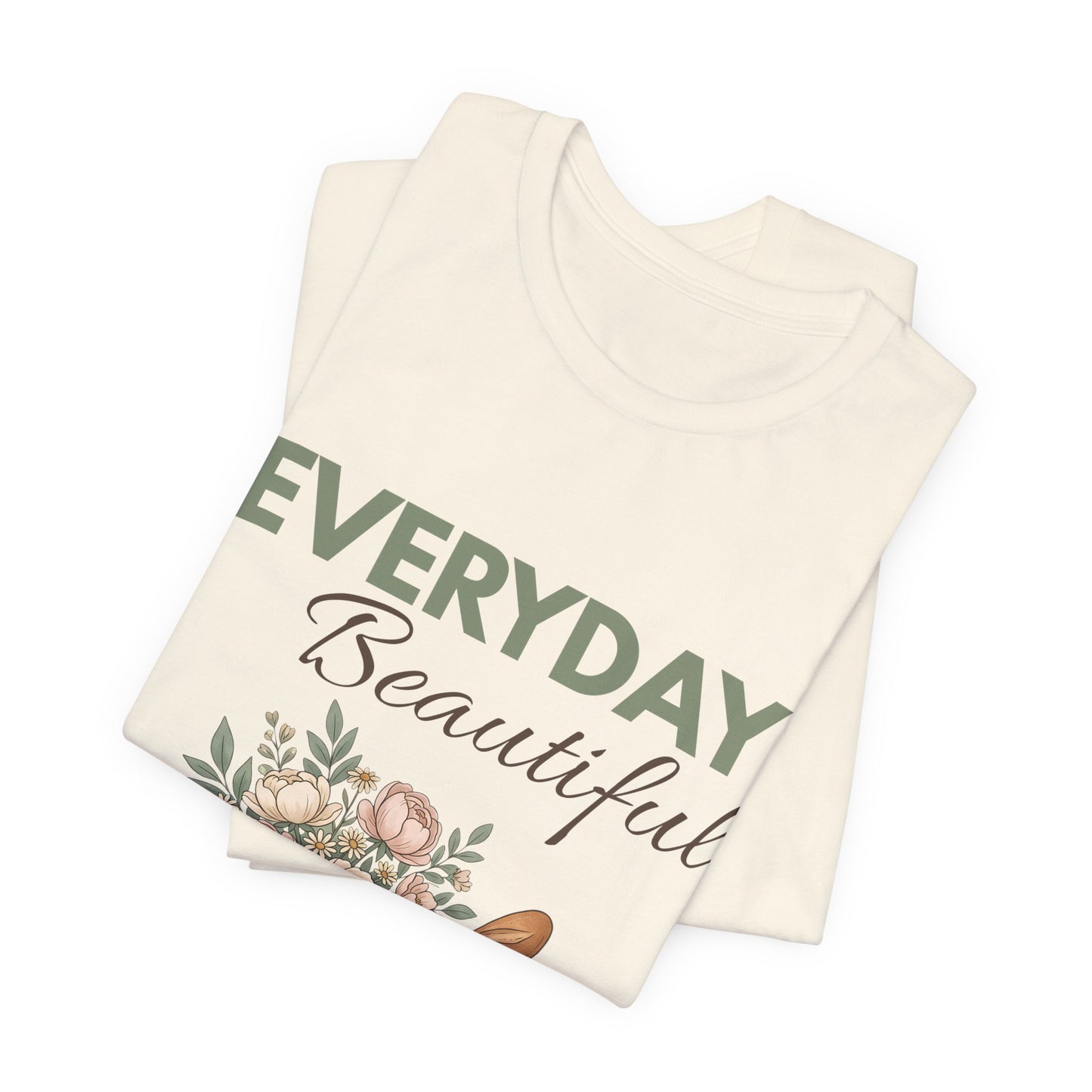 A folded natural colored t-shirt with 'EVERYDAY Beautiful' on the front.