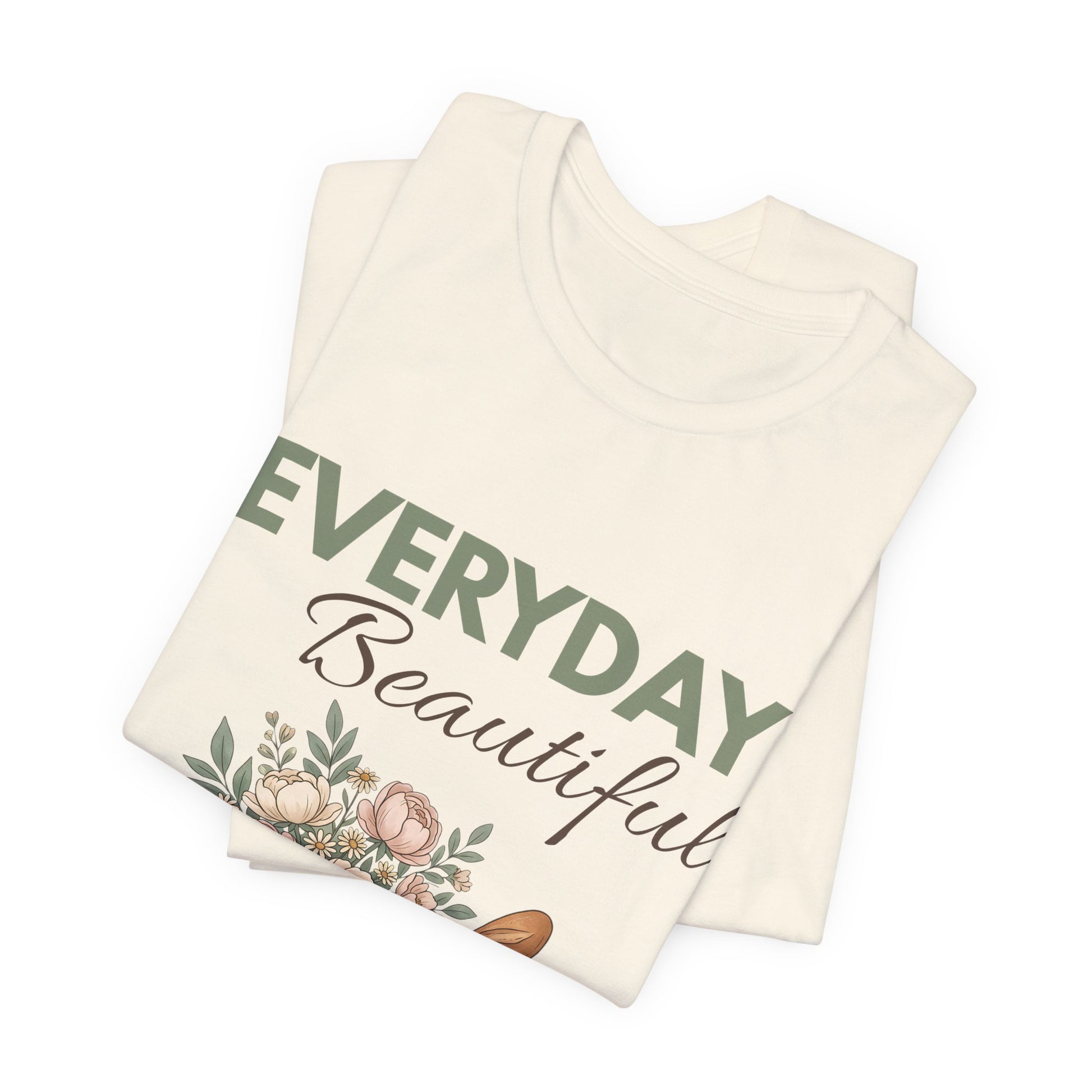 A folded natural colored t-shirt with 'EVERYDAY Beautiful' on the front.