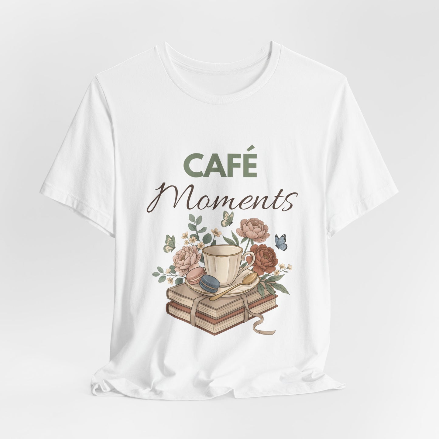 White t-shirt with 'Café Moments' design featuring a cup, books, and flowers on a white background