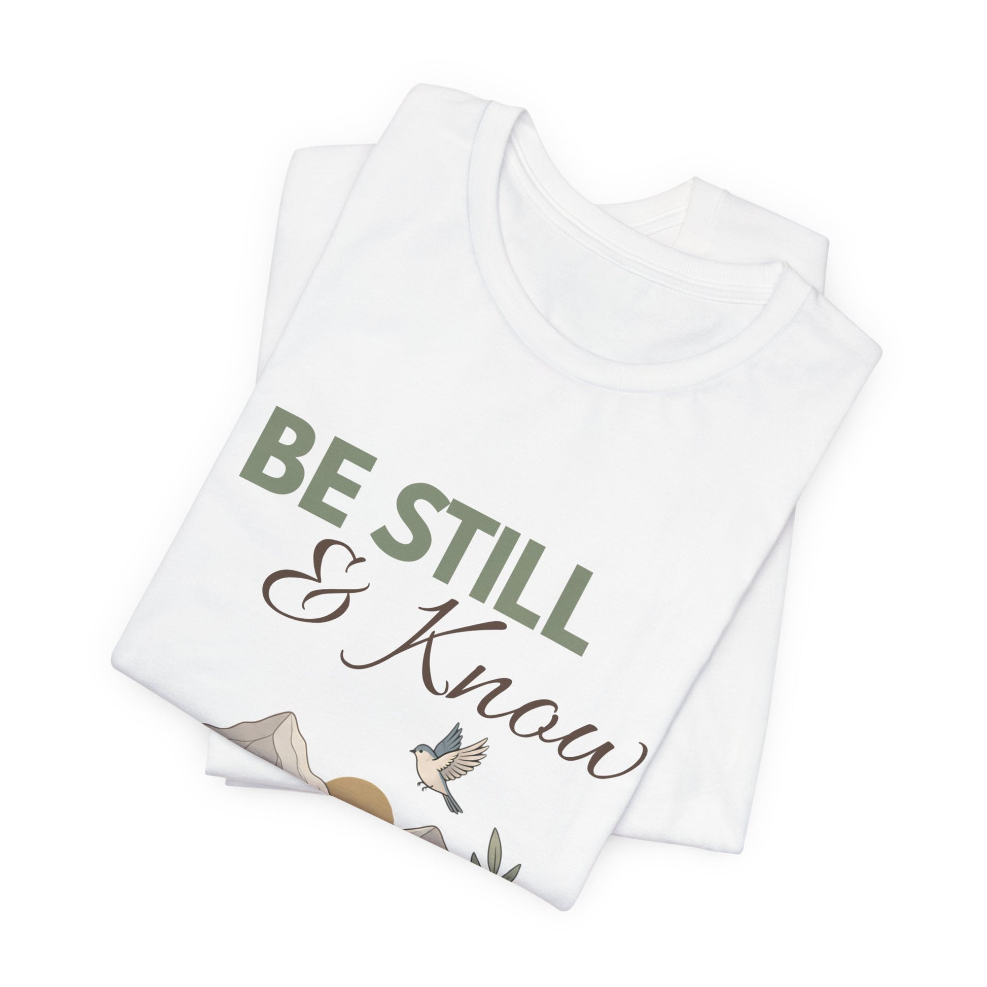 Folded white t-shirt with 'Be Still & Know' text and nature design on a white background