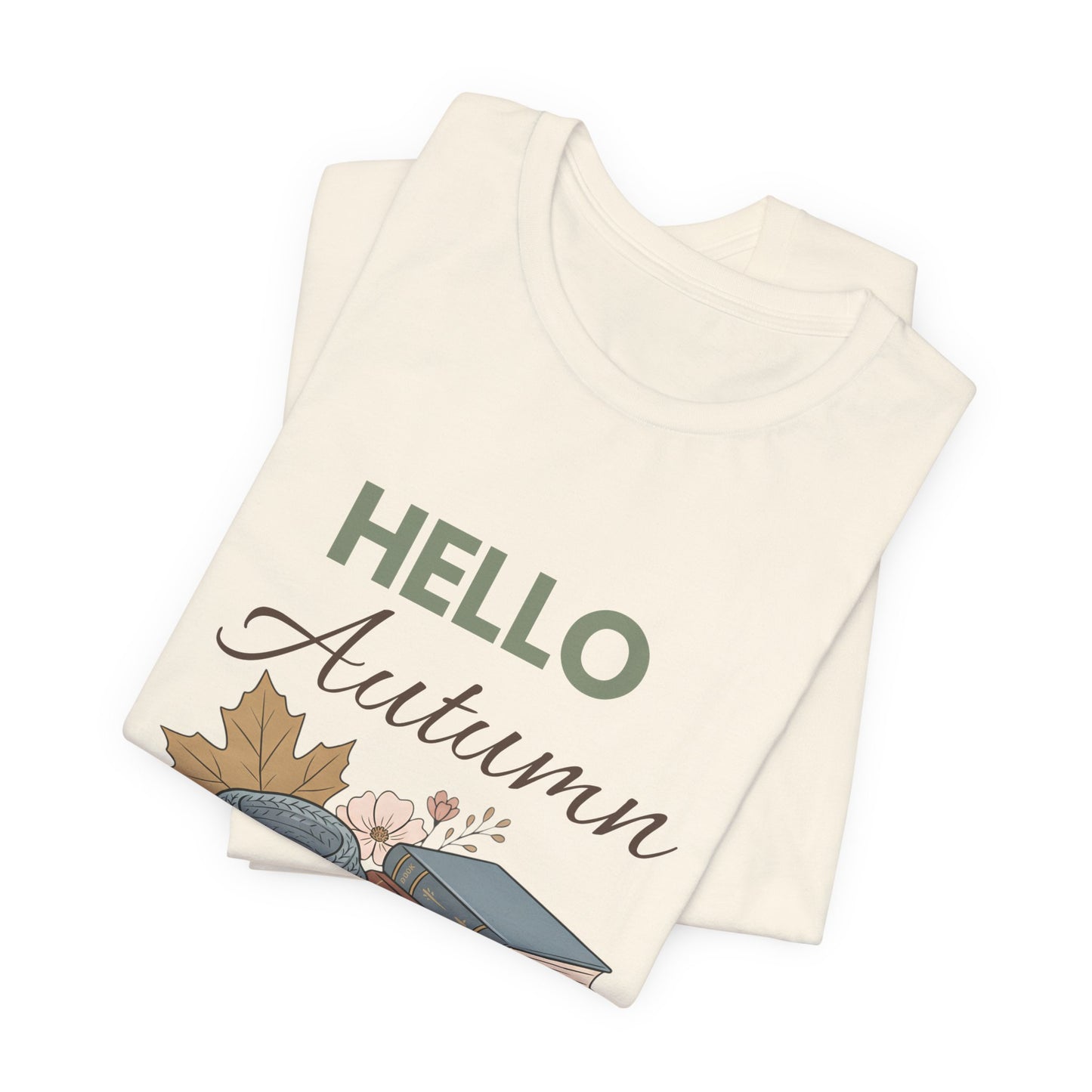 Folded natural colored t-shirt with 'Hello Autumn' text and leaf design on a white background