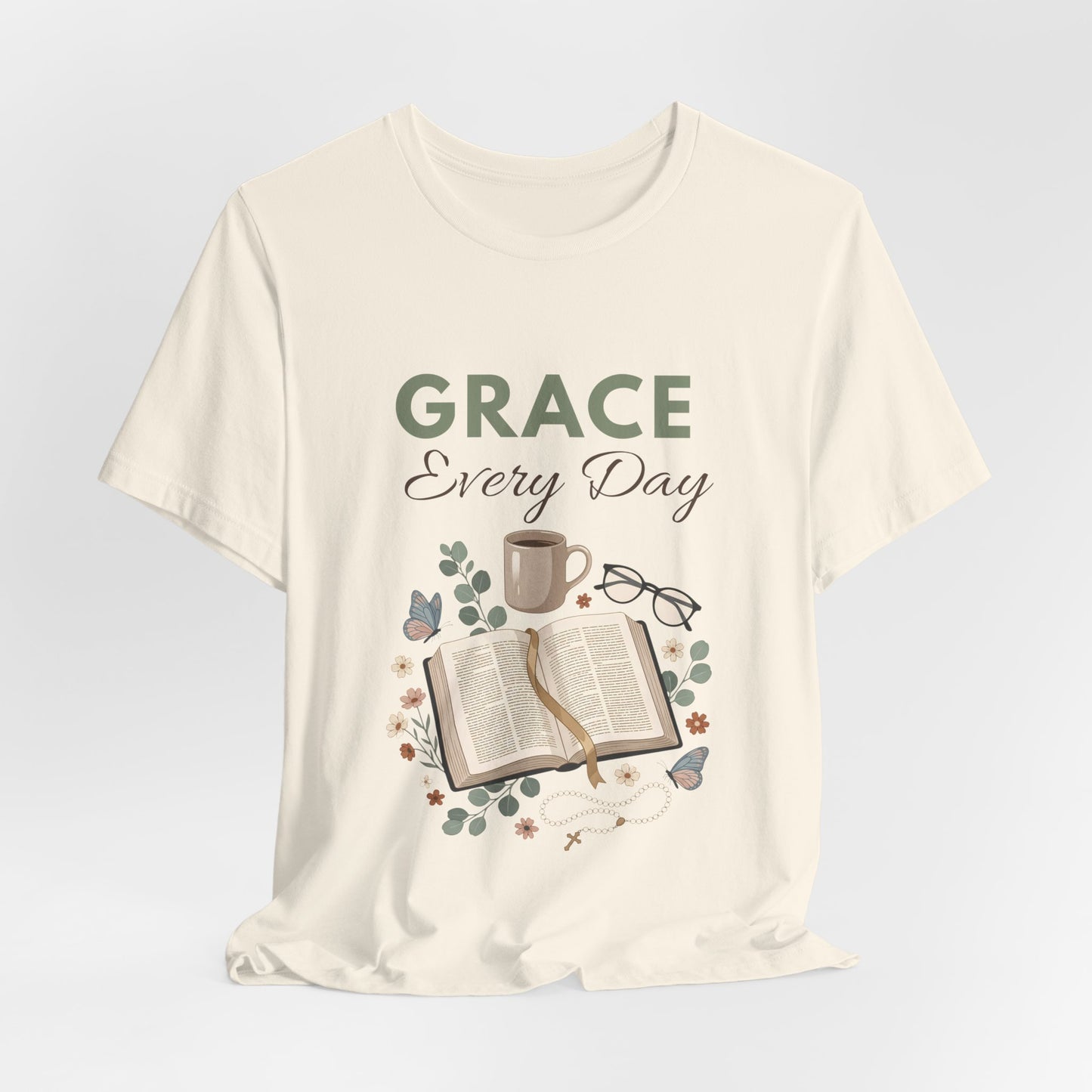 A natural colored t-shirt with 'Grace Every Day' text and book design on a light gray background