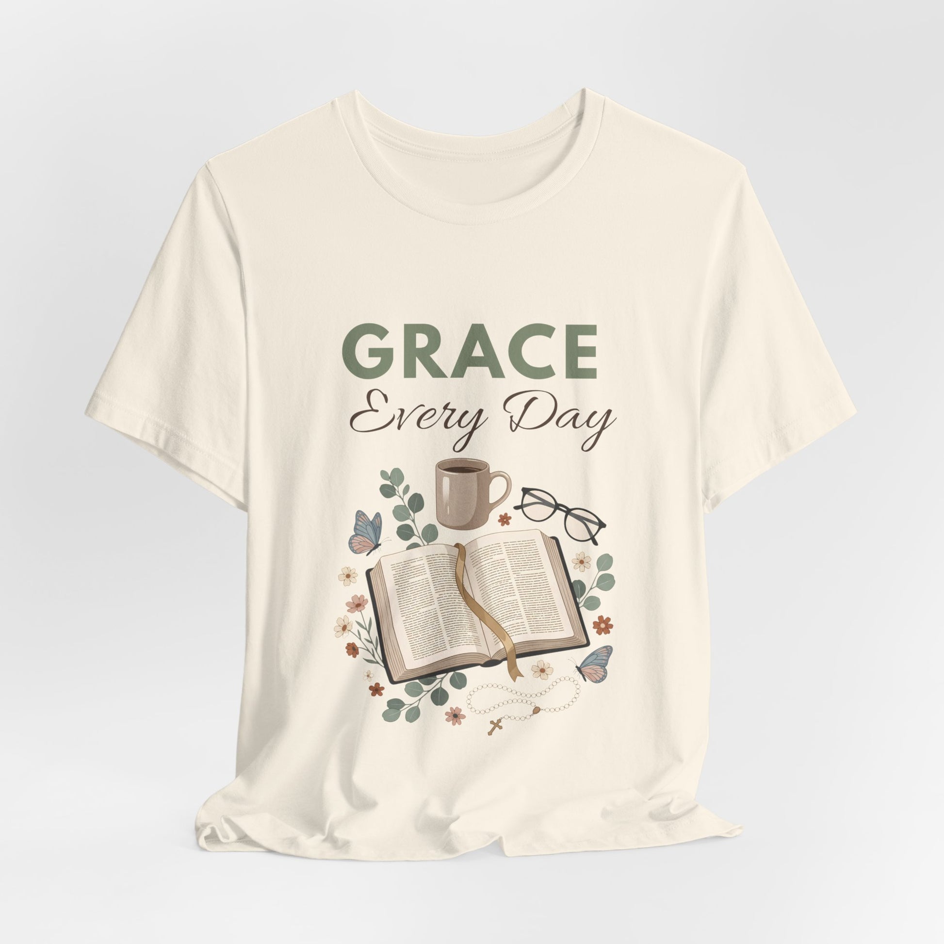 A natural colored t-shirt with 'Grace Every Day' text and book design on a light gray background