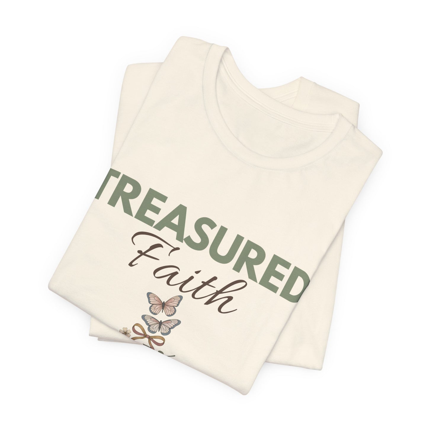 Folded natural colored t-shirts with 'Treasured Faith' text and butterfly design on a white background