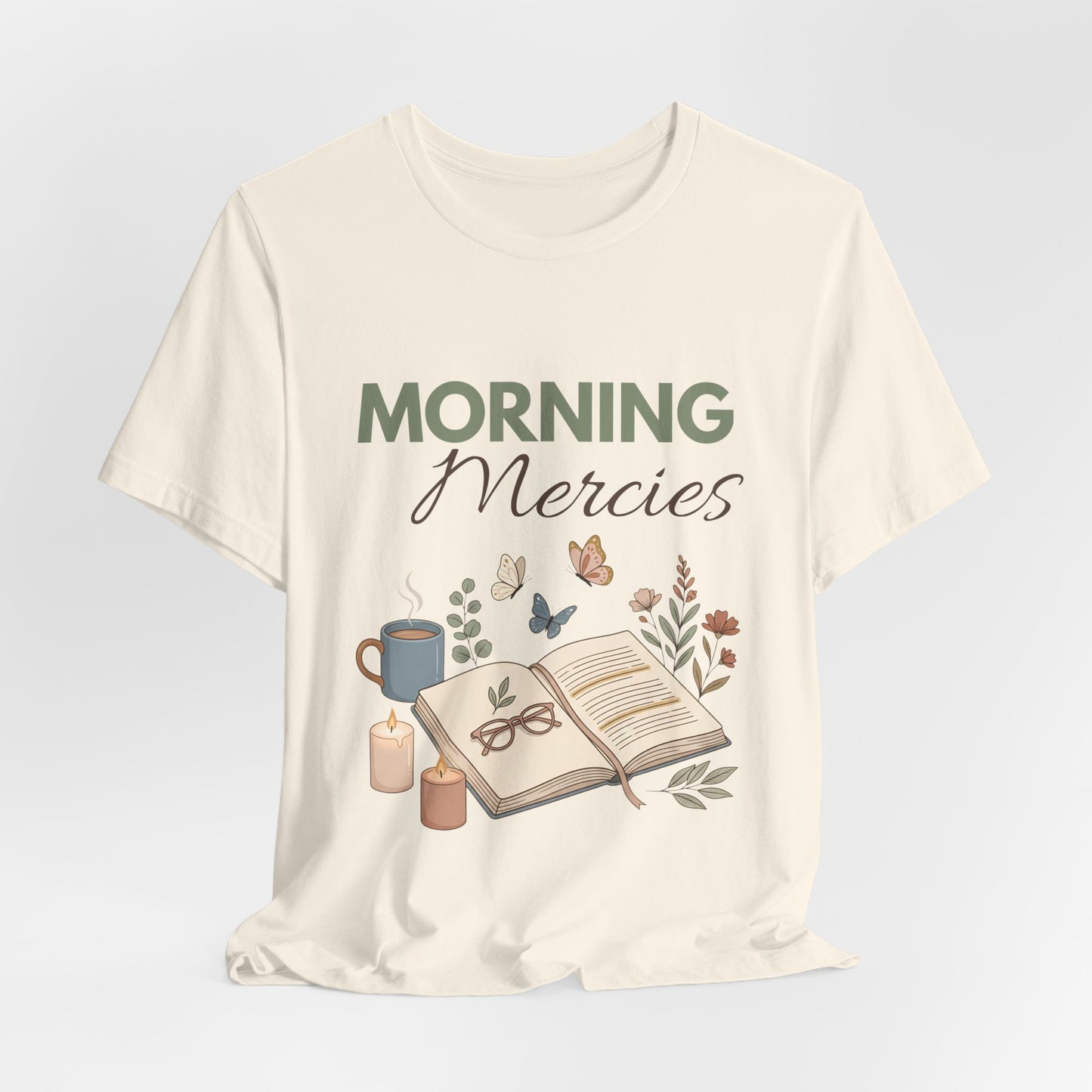 A natural colored t-shirt with 'Morning Mercies' text and illustrations on a light gray background