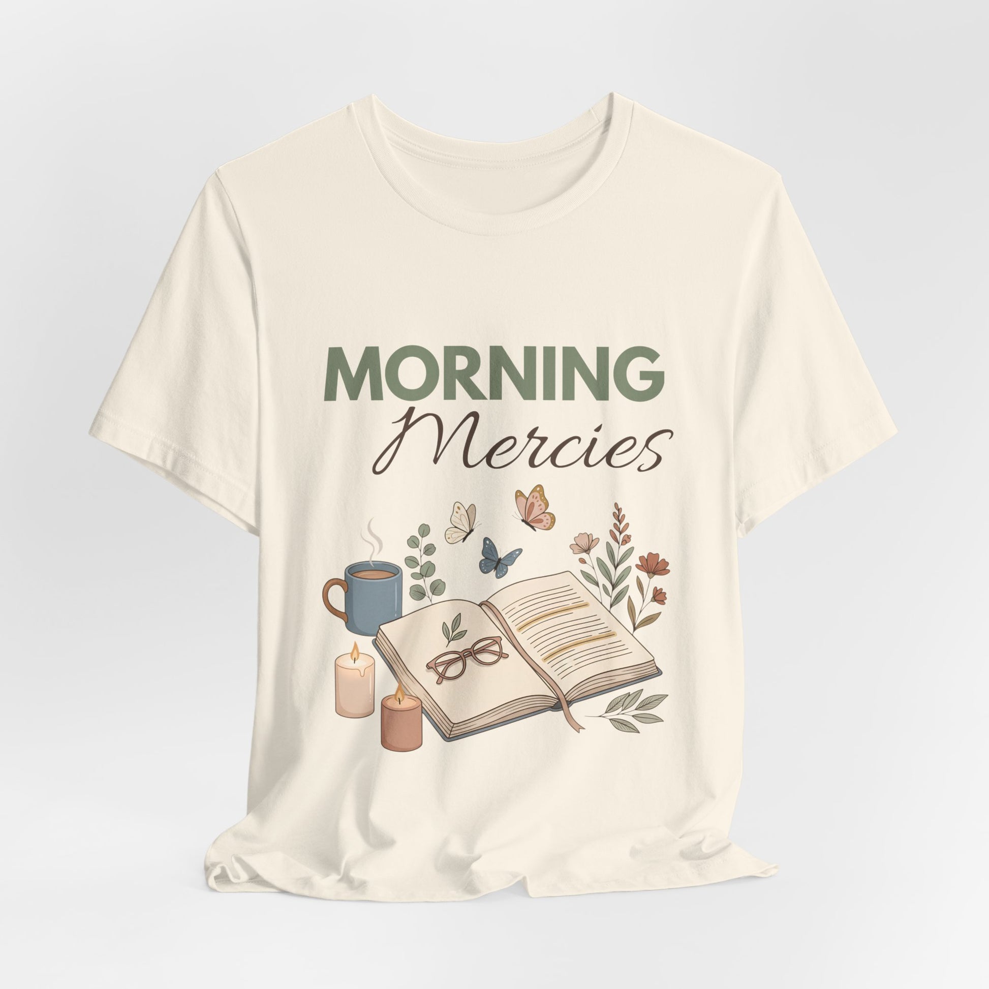 A natural colored t-shirt with 'Morning Mercies' text and illustrations on a light gray background
