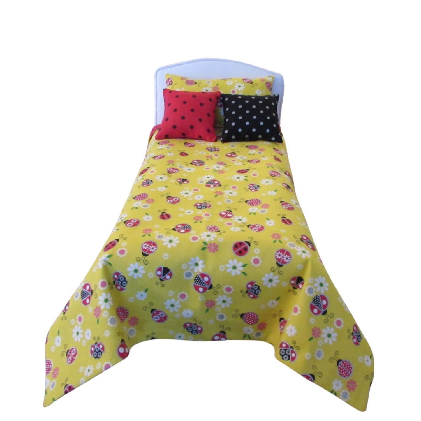 Yellow floral bedspread with colorful polka dot pillow on a white background