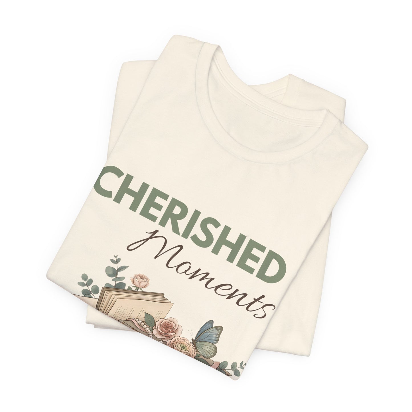 A folded natural colored t-shirt with 'CHERISHED Moments' on the front.