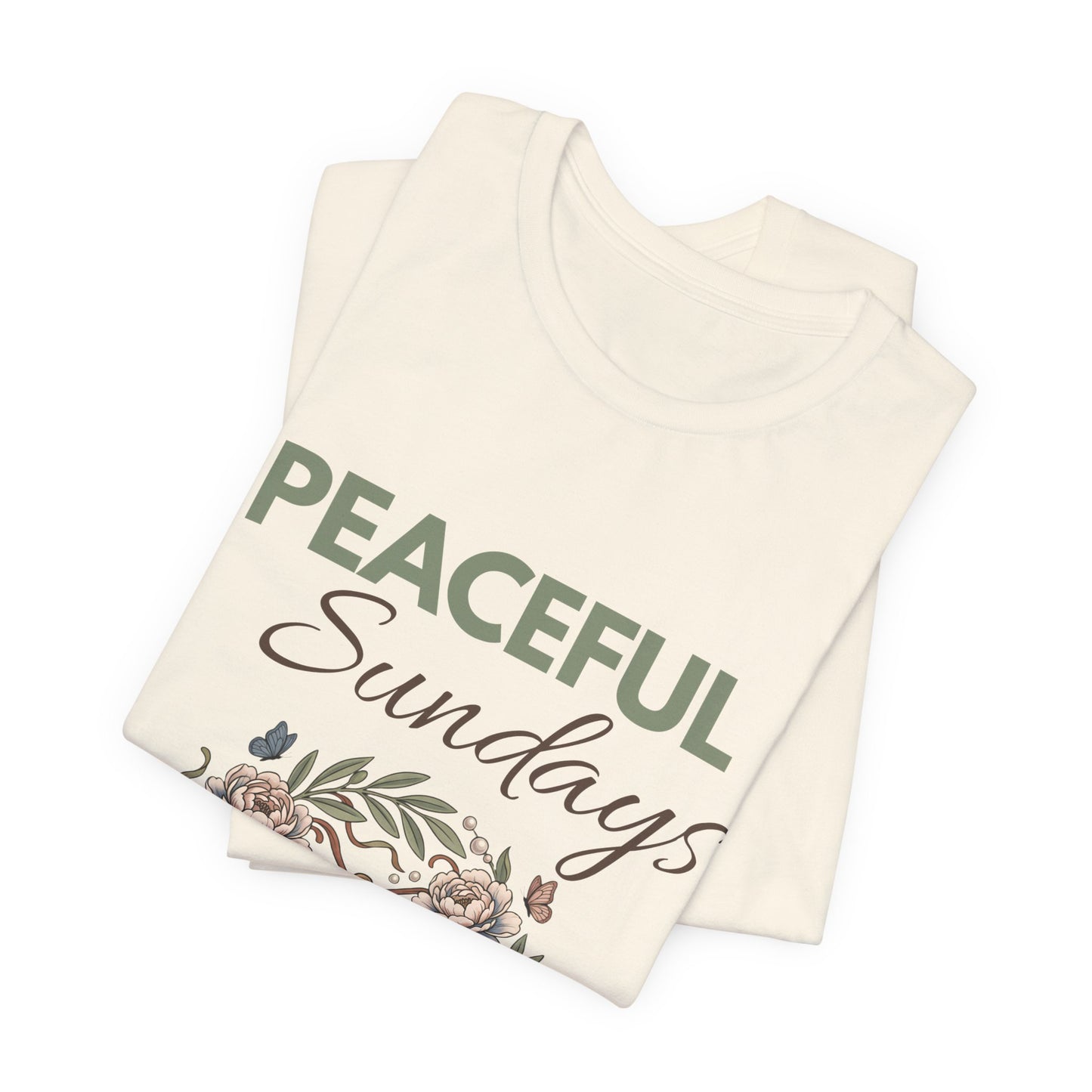 Folded natural colored t-shirt with 'Peaceful Sundays' text and floral design on a white background