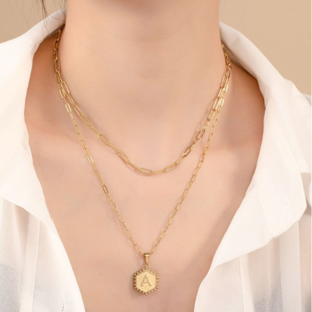 Woman wearing a two row brass double-sided hexagon initial A necklace
