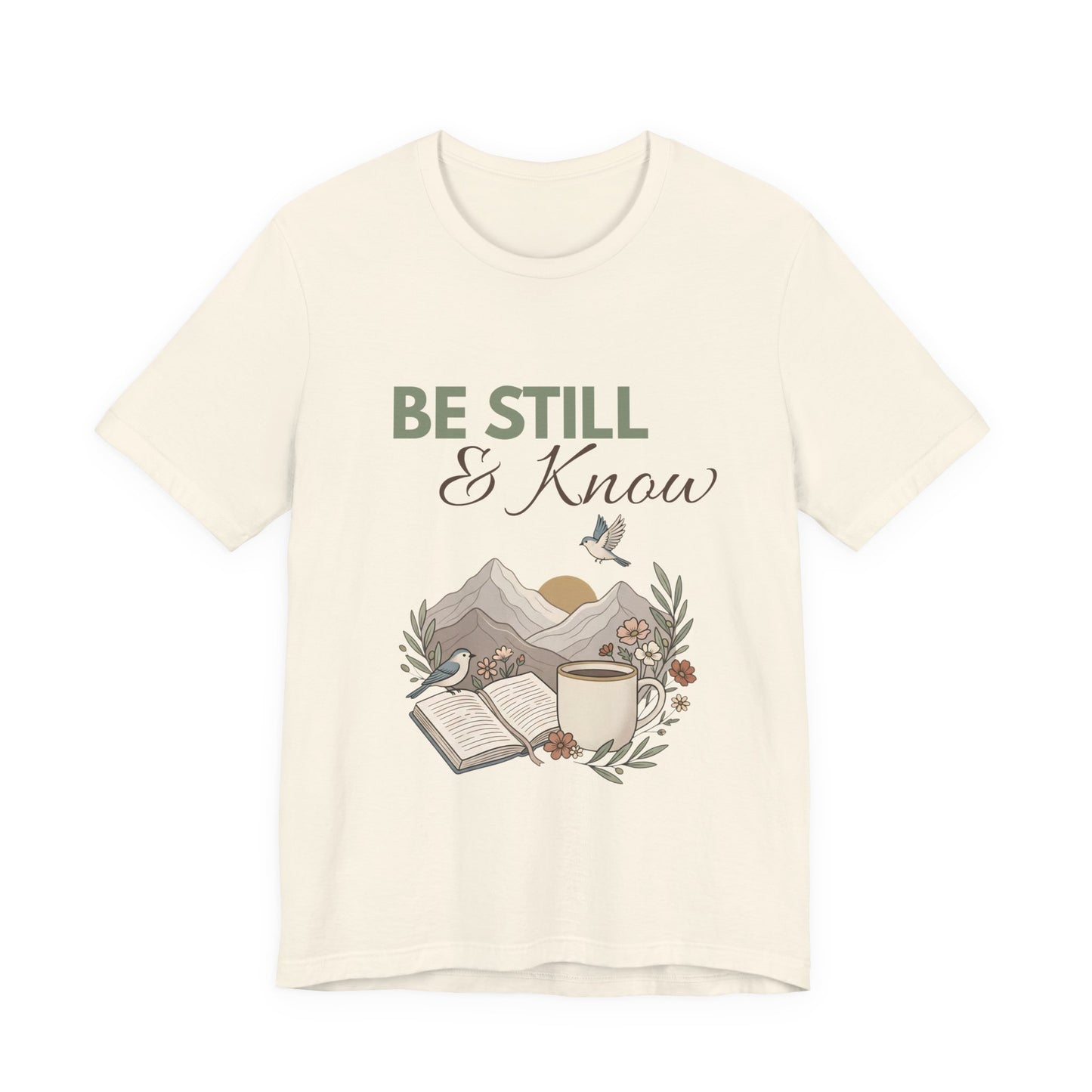 A natural colored t-shirt with 'Be Still & Know' text and nature-themed design on a white background
