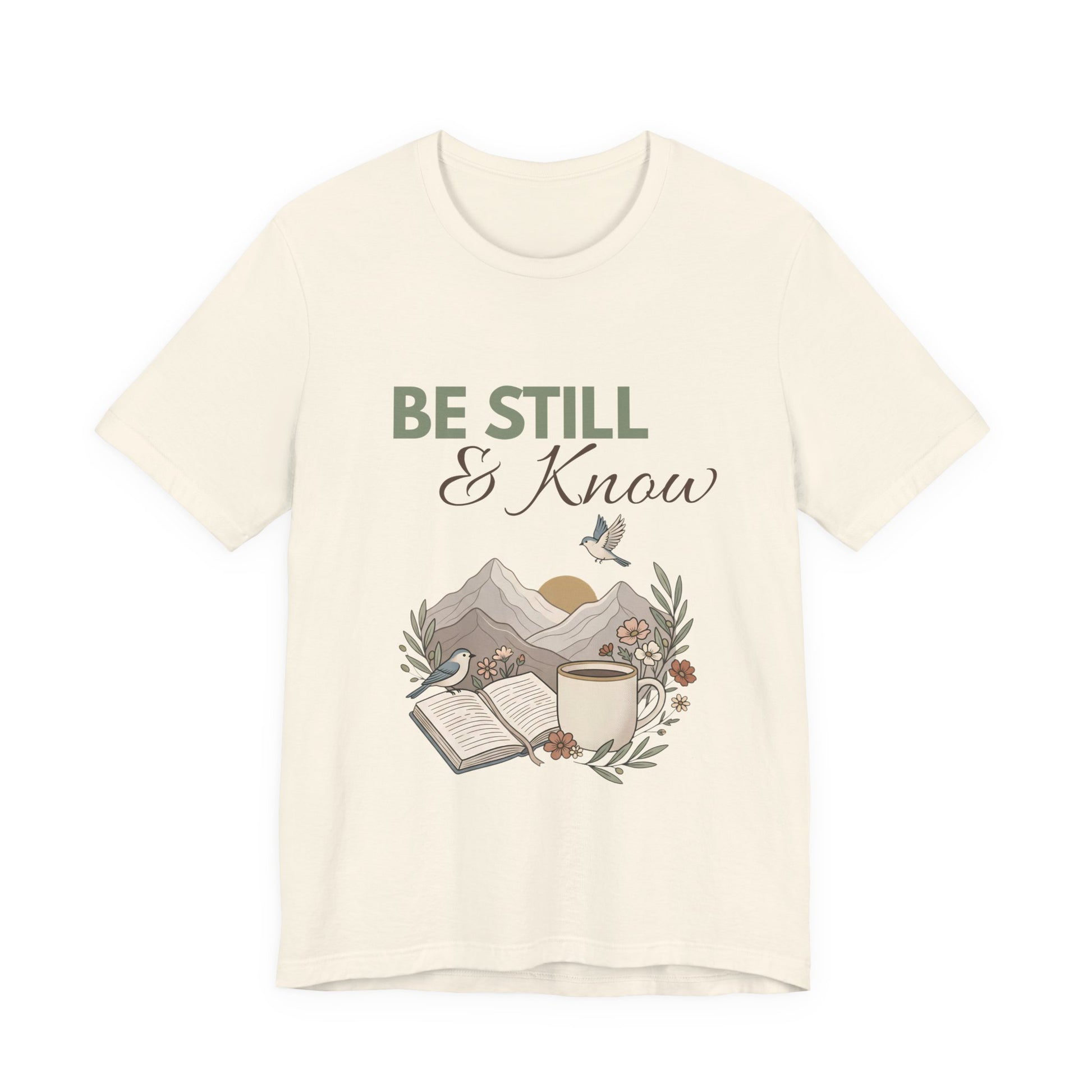 A natural colored t-shirt with 'Be Still & Know' text and nature-themed design on a white background