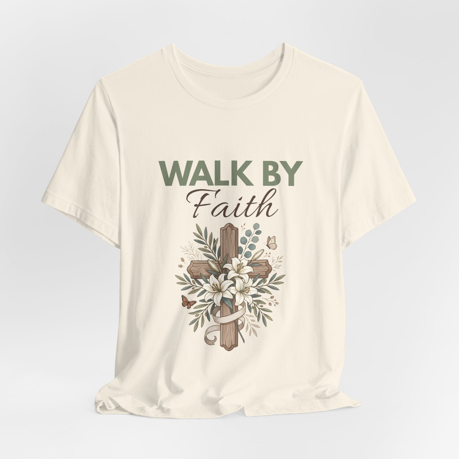A natural-colored t-shirt with 'Walk by Faith' text and cross design on a light gray background