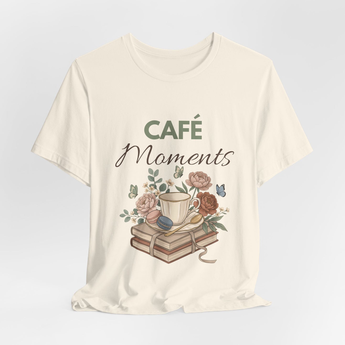 Natural colored t-shirt with 'Café Moments' design featuring a cup, books, and flowers on a light gray background