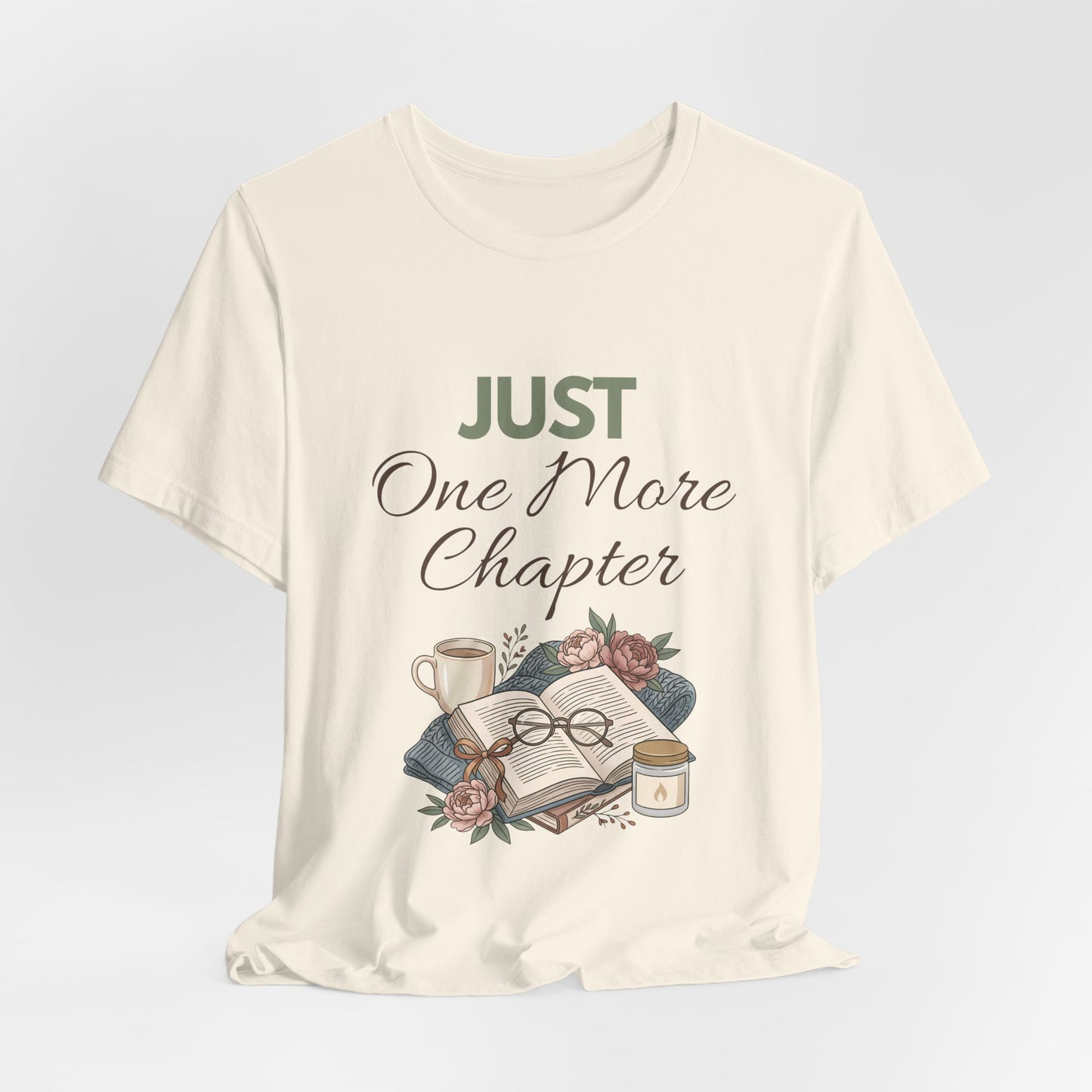 Natural colored t-shirt with 'Just One More Chapter' text and book-themed graphics on a light gray background