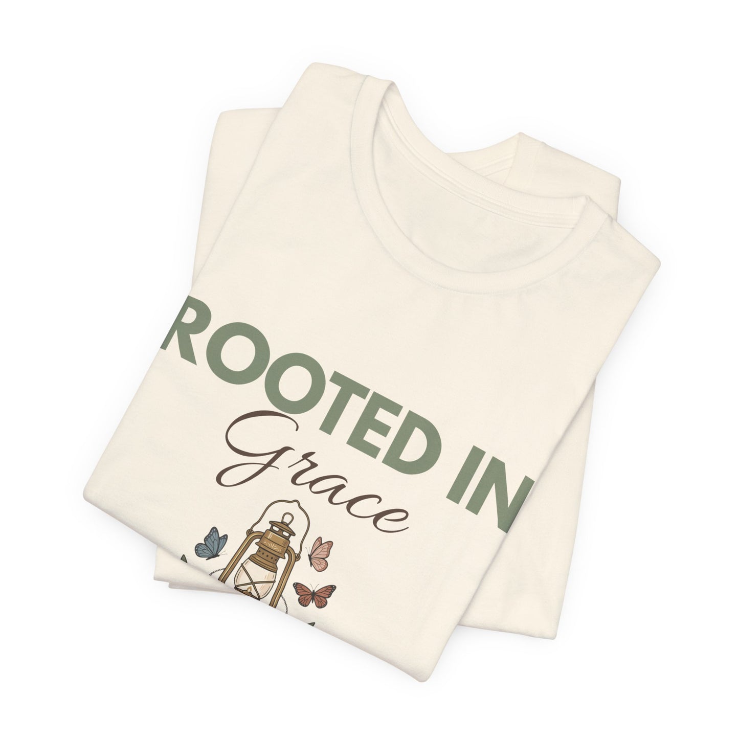 Folded natural colored t-shirt with 'Rooted in Grace' text and illustrations on a white background