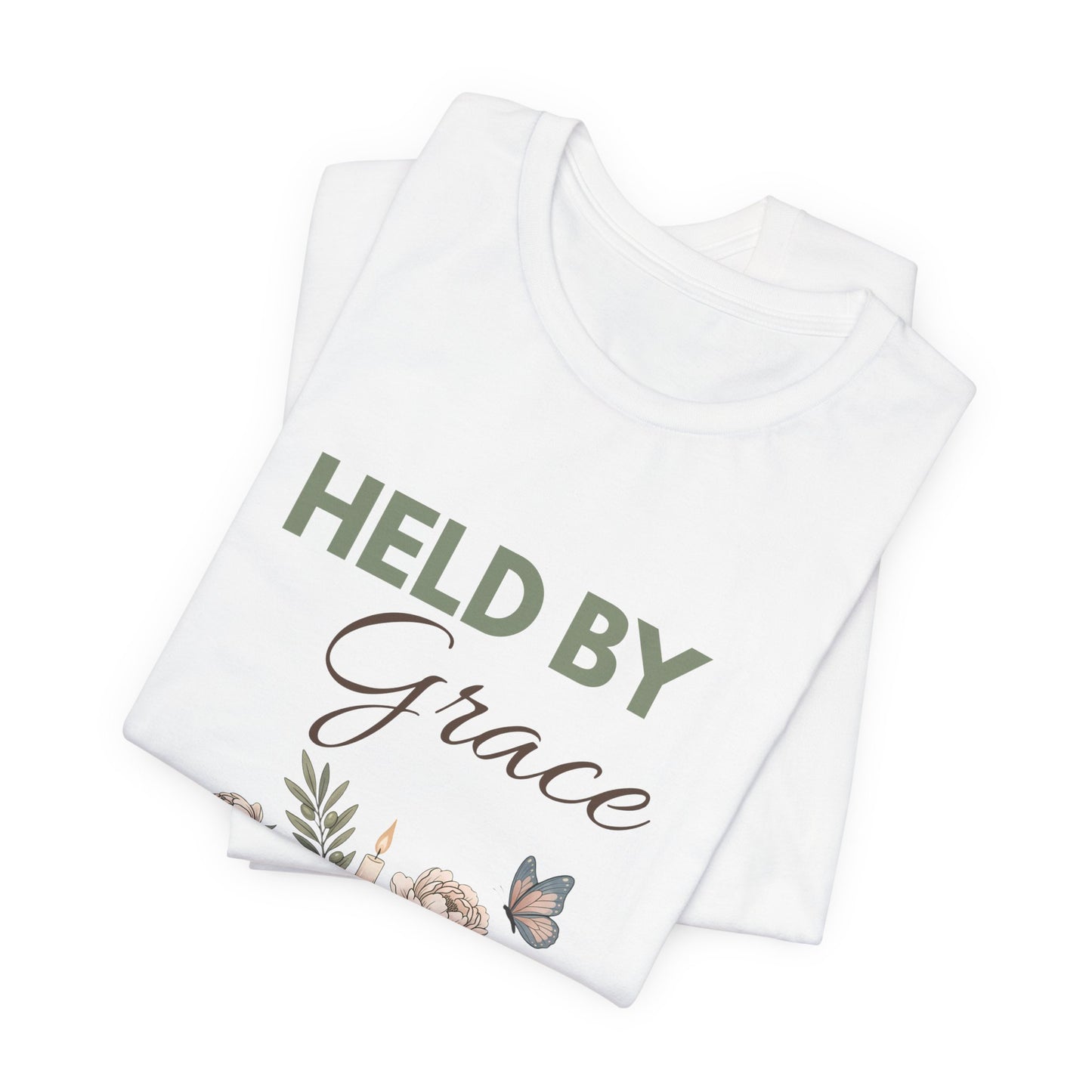 Folded white t-shirt with 'HELD BY Grace' text and floral design on a white background