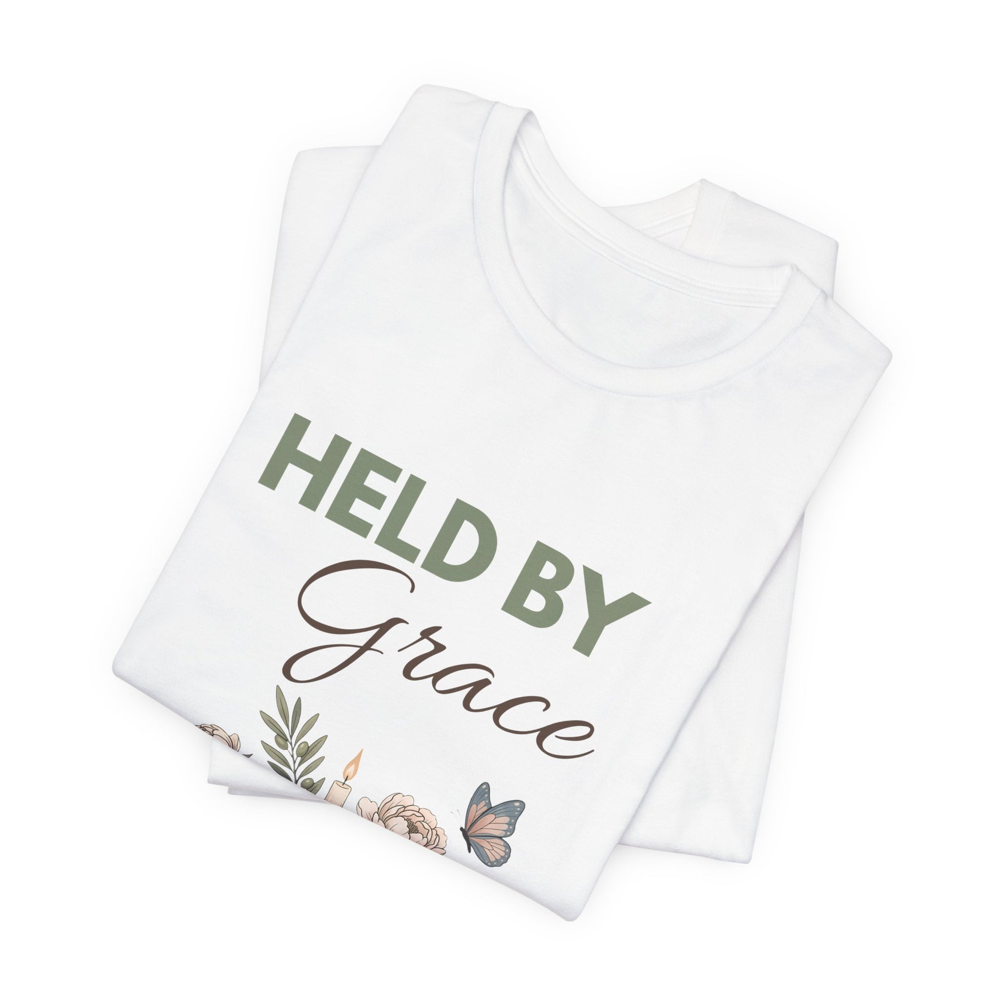 Folded white t-shirt with 'HELD BY Grace' text and floral design on a white background