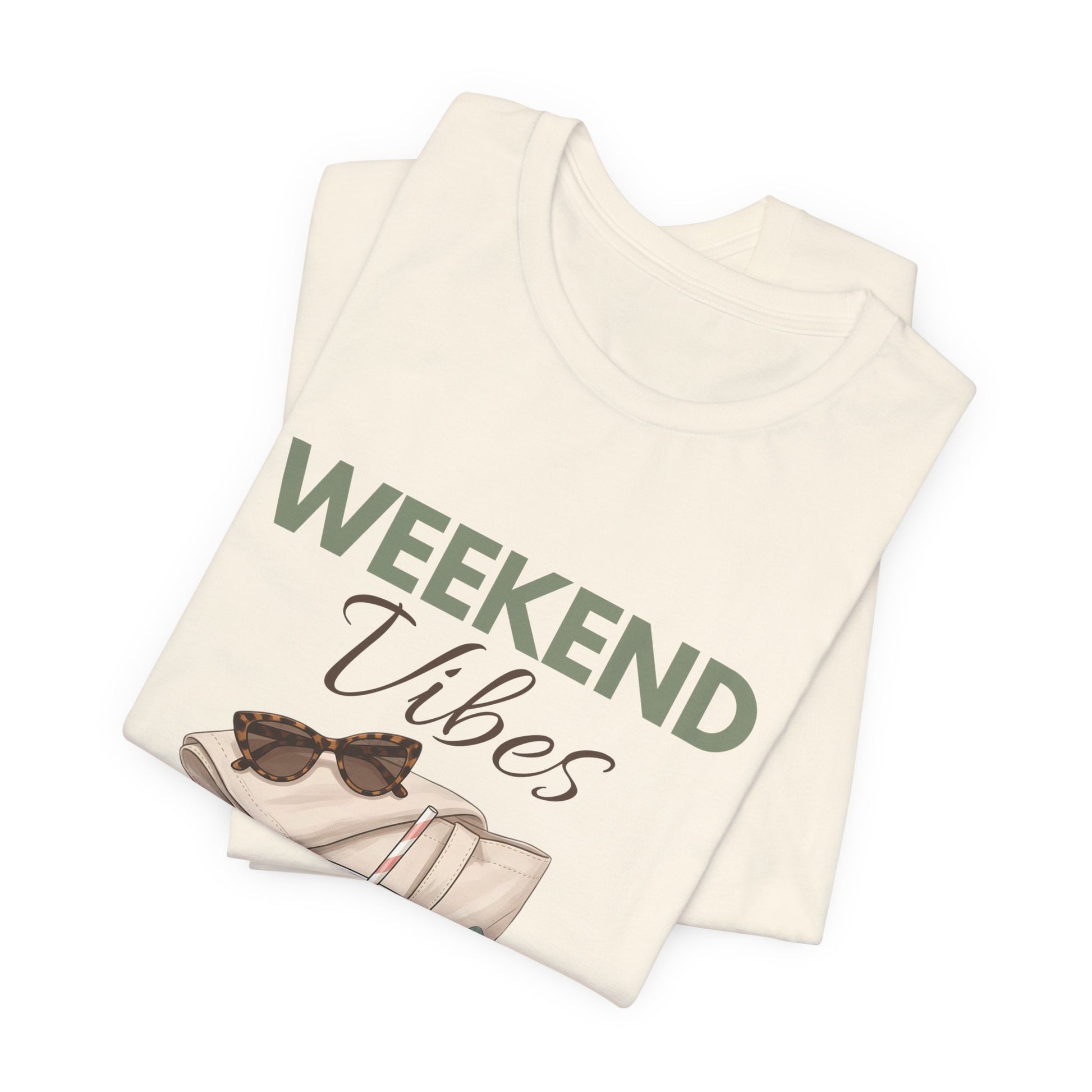 Folded natural colored t-shirt with 'Weekend Vibes' text and sunglasses graphic on a white background