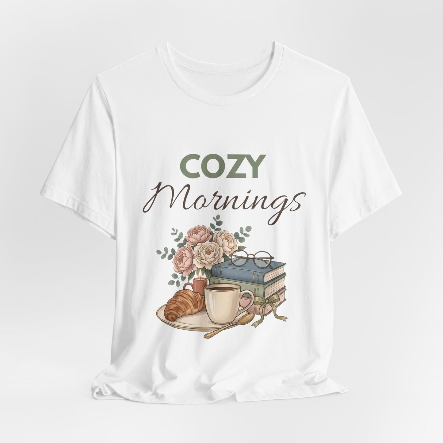 White t-shirt with 'Cozy Mornings' graphic featuring a cup, books, and flowers on a white background
