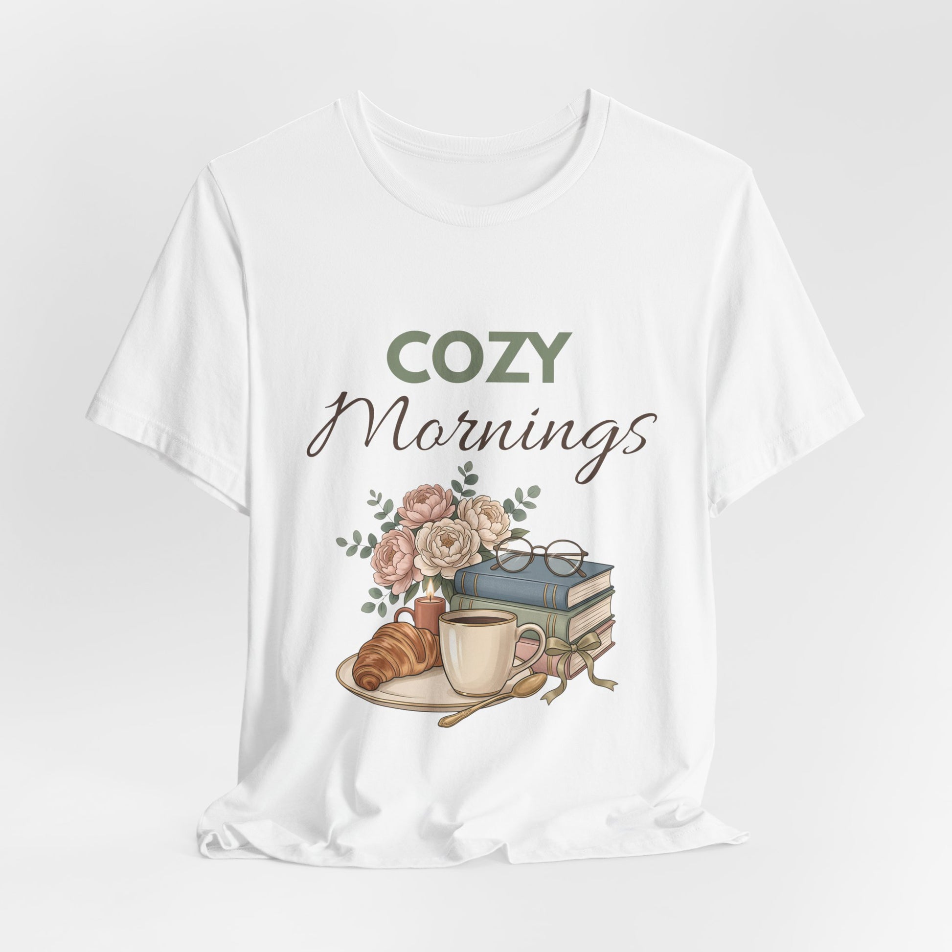 White t-shirt with 'Cozy Mornings' graphic featuring a cup, books, and flowers on a white background