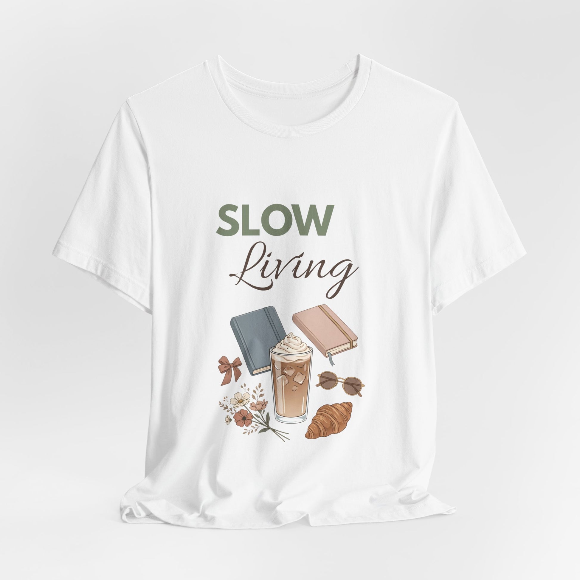 White t-shirt with 'Slow Living' graphic design featuring a coffee cup, book, and croissant on a white background.