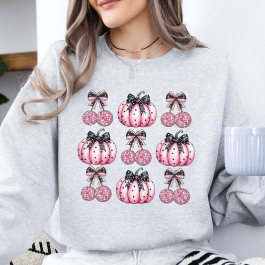 Person wearing a light gray sweatshirt with pink pumpkin designs and black bows.