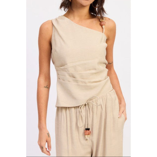 Woman wearing a beige one-shoulder top and matching pants on a white background