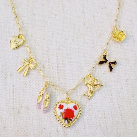 Gold necklace with heart-shaped pendant and floral design on a textured white background