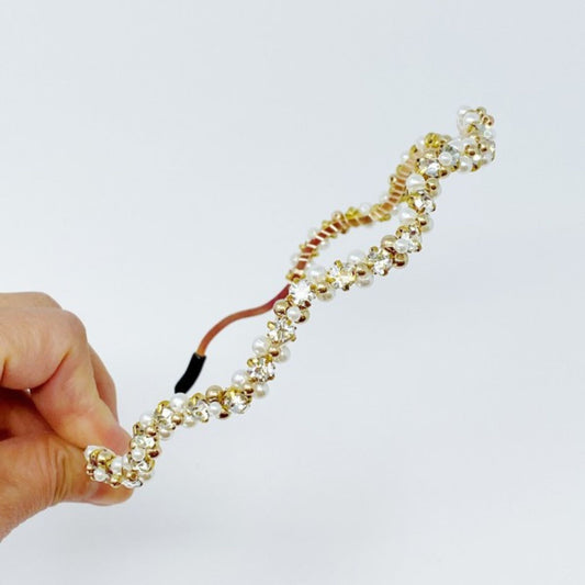 Hand holding a beaded headband against a white background