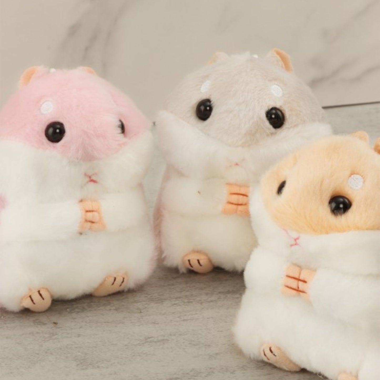 Three plush toys resembling hamsters on a neutral background