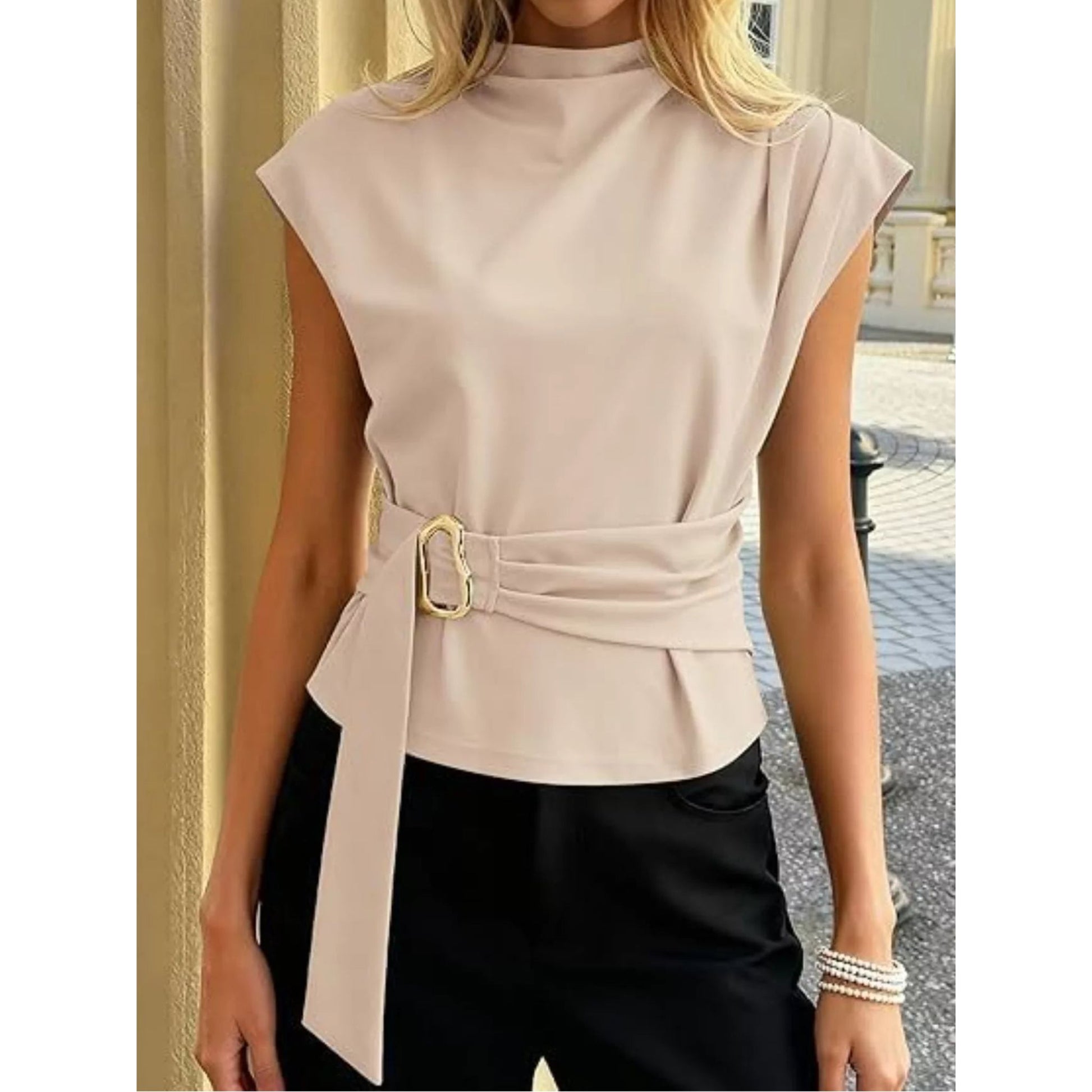 Woman wearing a beige sleeveless top with a belt and black pants on a blurred street background