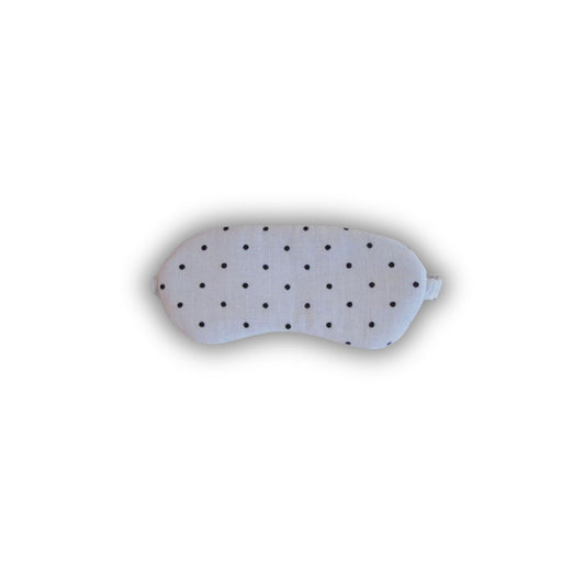 White sleep mask with black polka dots on a white background
