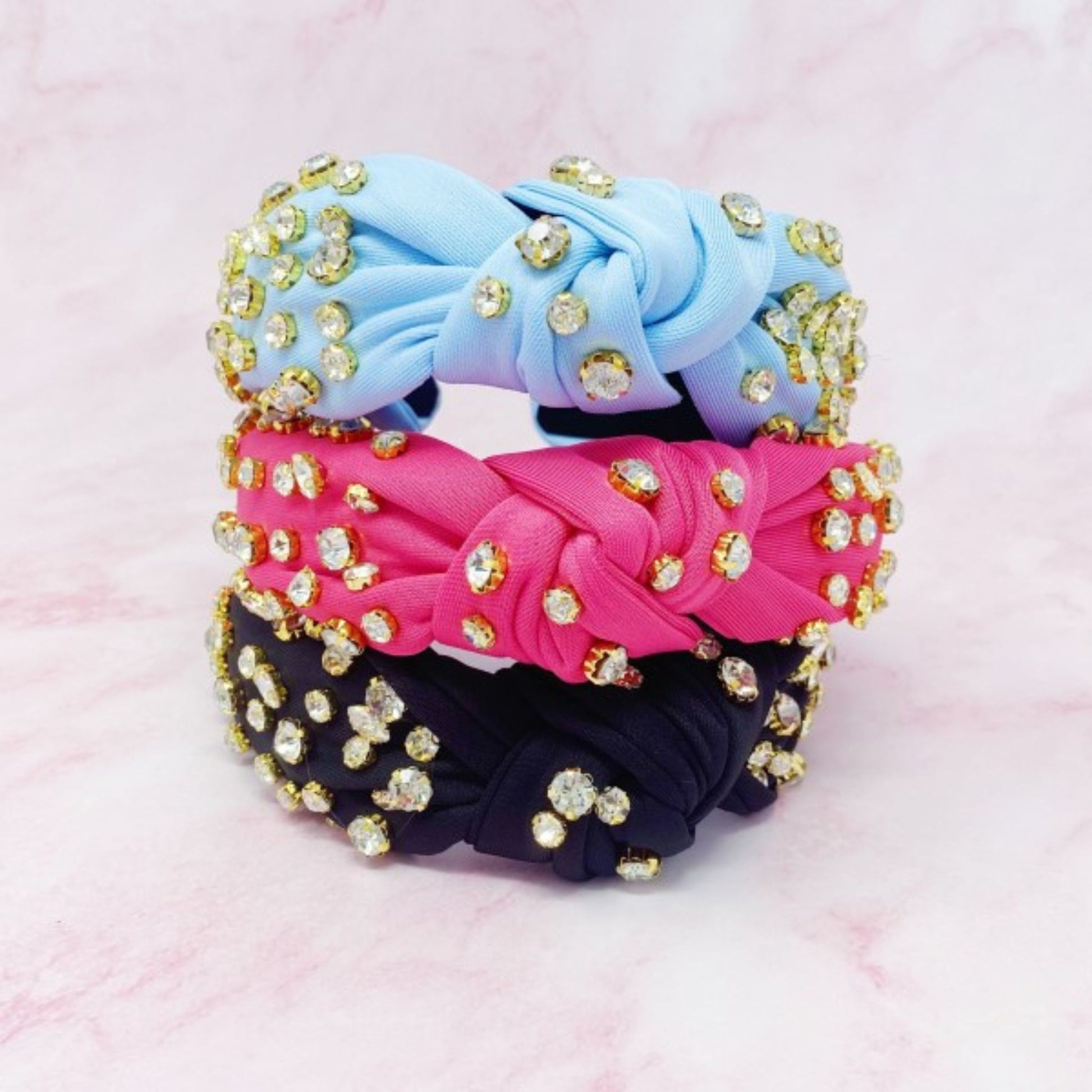 Three colorful hair ties with rhinestones on a pink background