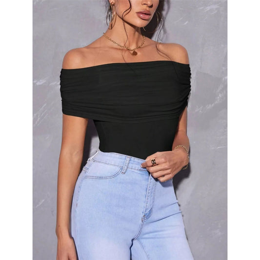 Person wearing a black off-shoulder top and light blue jeans against a gray background