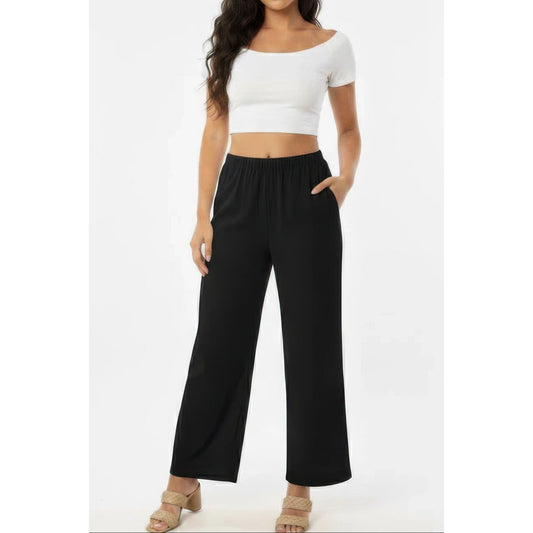 Woman wearing a white crop top and black wide-leg pants on a white background